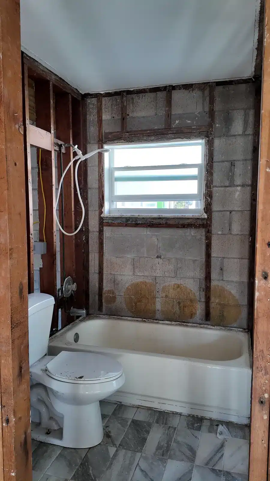 New Port Richey bathroom during strip-out, with the old tub and toilet against open walls