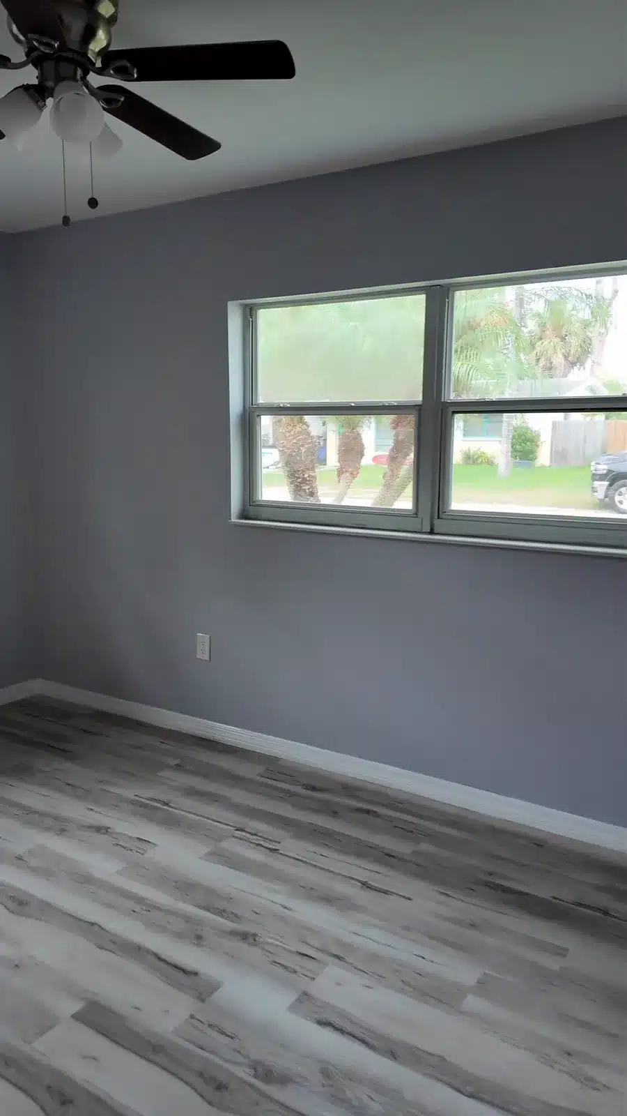 Renovated bedroom with blue-grey walls, a ceiling fan and new plank flooring