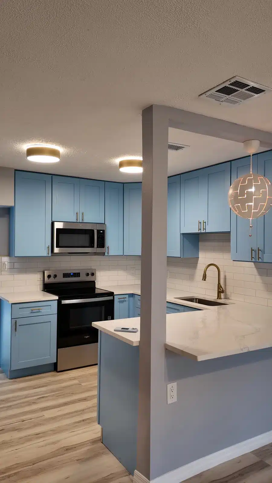 The new peninsula opening between the kitchen and living area, with a pendant light above